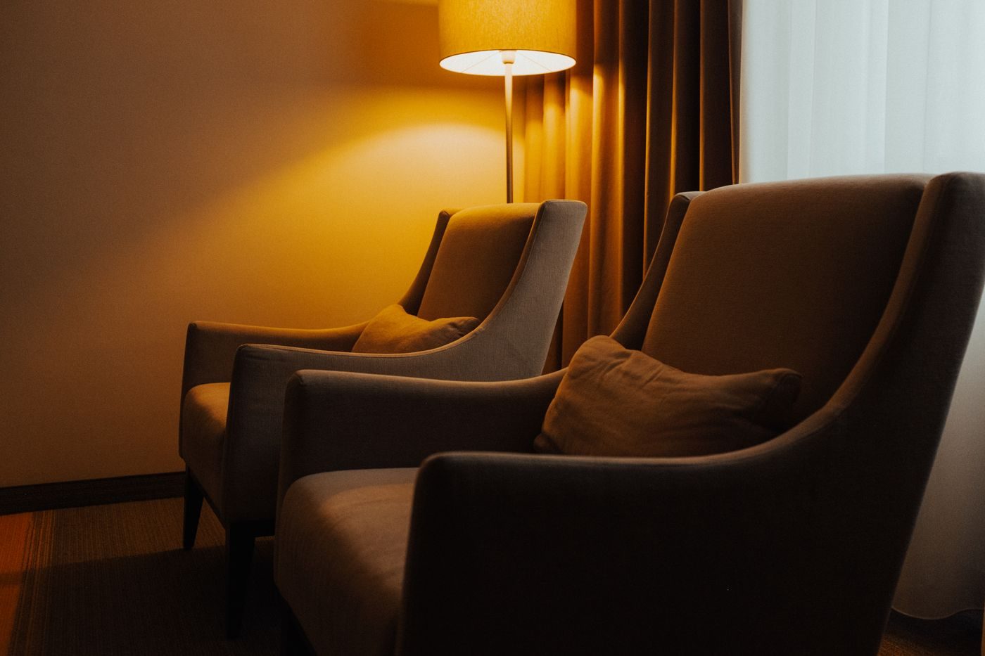 Two armchairs in a living room lit by a warm floor lamp